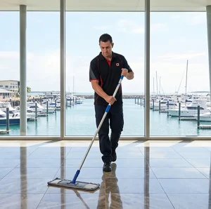 Commercial cleaner mopping hallway with docked boats in the background