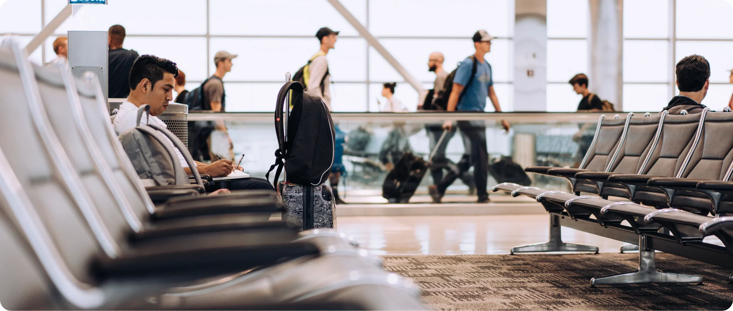 Person seated in airport waiting area near boarding gate