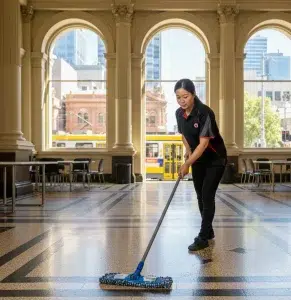 Commercial cleaner mopping hallway with tram in background